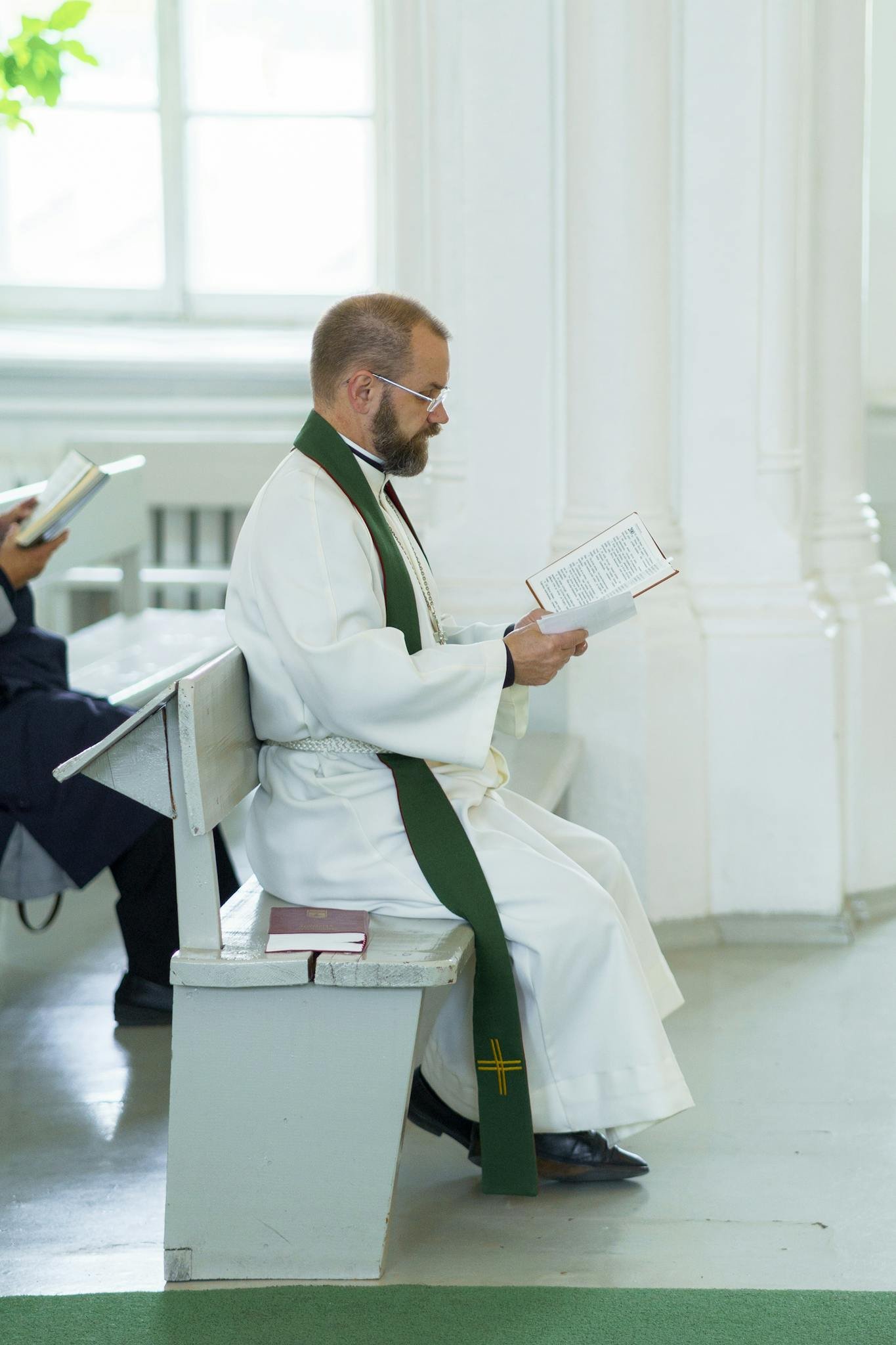 A priest in robes reading inside a serene church, conveying peace and spirituality.
