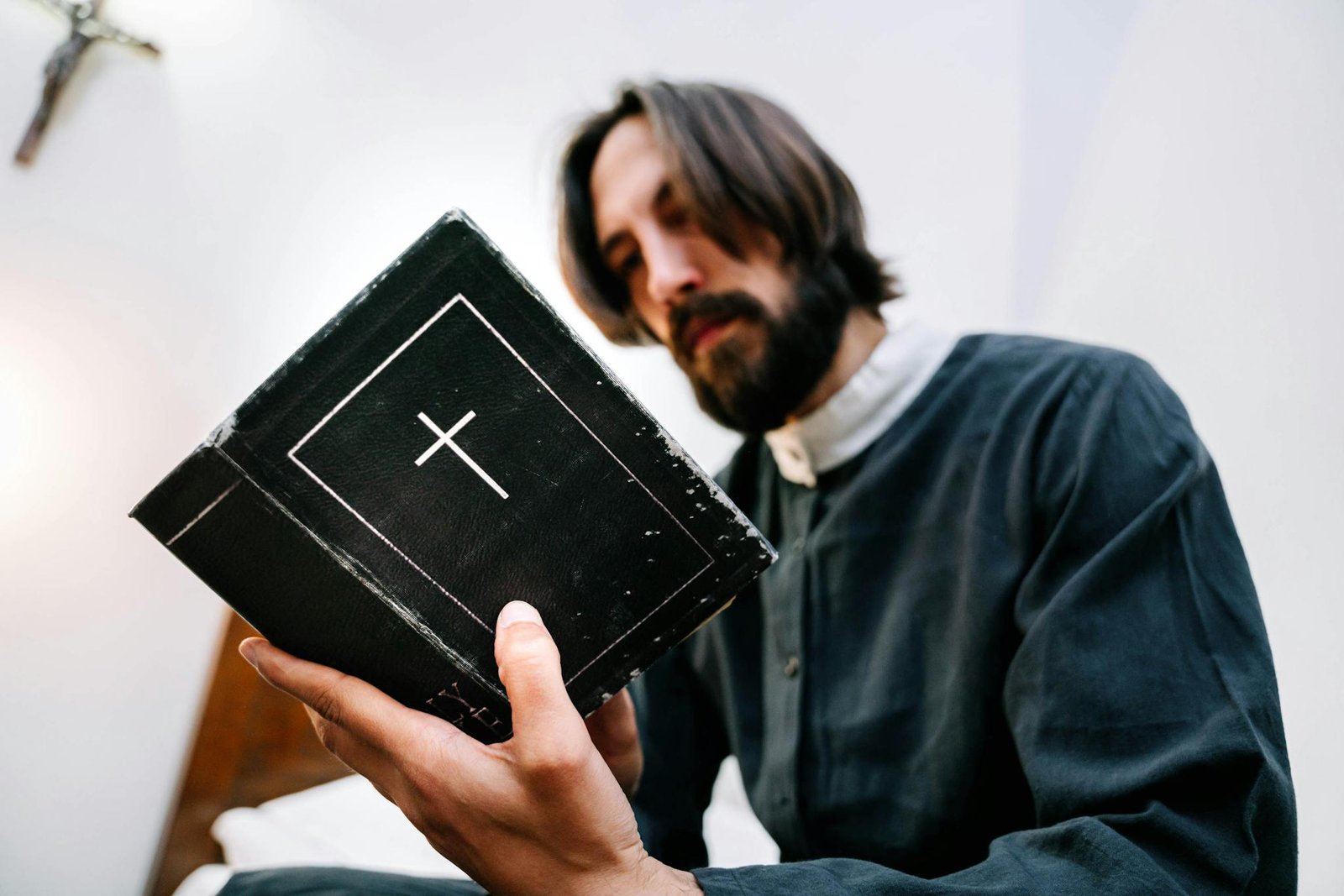 A priest reading a Bible, symbolizing faith and devotion in a serene indoor setting.